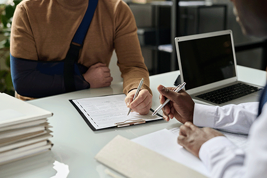 person with a cast signing a document